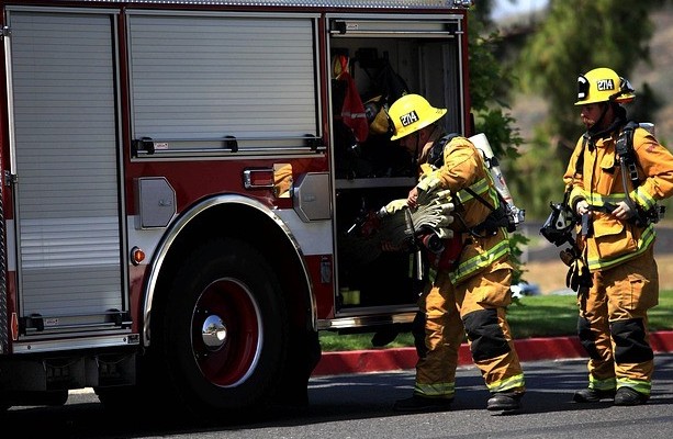 two fireman returning gear to the firetruck