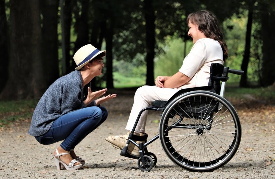 woman squatting to talk with person in wheelchair