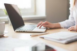 Woman sitting at a table using her laptop.