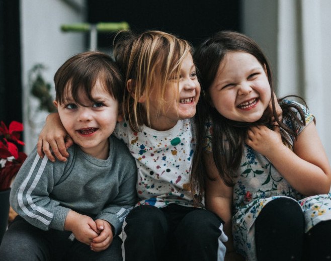 3 children sitting together laughing