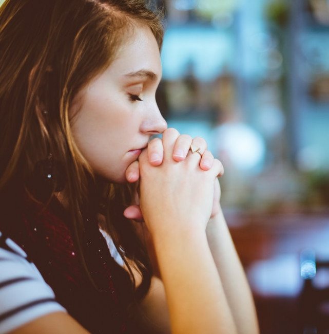 Young woman praying with hands folded